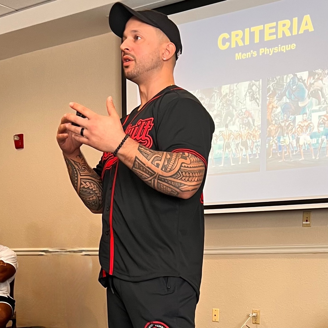 Coach Nando teaching during an in-person physique seminar